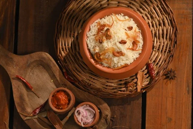 Fragrant white basmati rice or basanti pulao garnished with fried cashews, raisins, and beresta (fried onions), served in a traditional clay handi on a woven mat. This premium menu option showcases wedding catering services in Kolkata by Food Chakra.