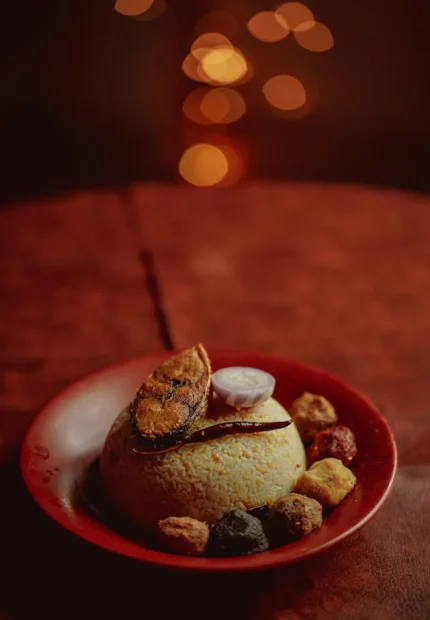 Authentic Bengali wedding menu featuring a fried Ilish (Hilsa) fish steak atop a warm dome of bhuni khichuri, garnished with a slice of onion and red chili, by Food Chakra in Kolkata. | Image for Food Chakra – Trusted Catering Services in Kolkata