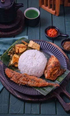 A premium multi-cuisine Indonesian Nasi Padang platter featuring fried fish, spicy chicken, and greens on a banana leaf, showcasing global destination wedding menu options by Food Chakra in Kolkata. | Image for Food Chakra – Trusted Catering Services in Kolkata
